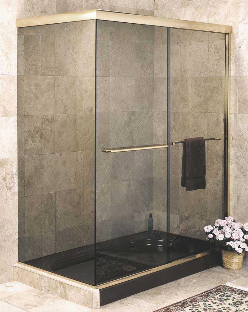 Frameless brass shower stall enclosure without a corner post. Uninterrupted glass runs from the wall to the sliding doors.