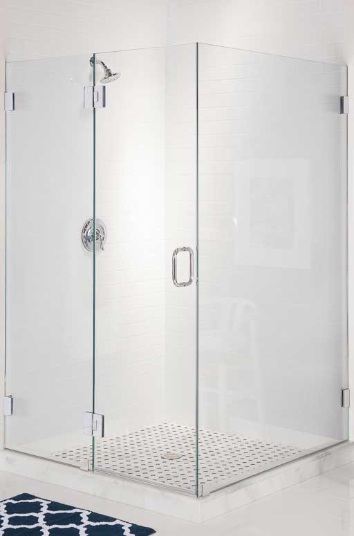 A shower enclosure without any framing. Silver-colored hinges attach the glass to the wall and basin.