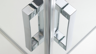 Silver-colored door hinges on a 90 degree stall corner of a frameless glass shower enclosure.
