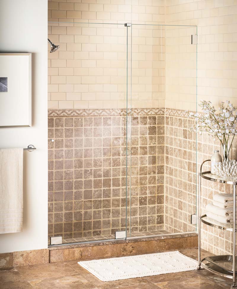 Frameless shower enclosure with a sliding door affixed to a bottom roller system and no top header or framing.